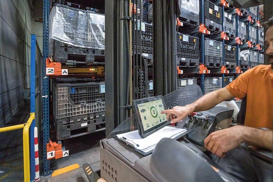 Um operador manuseia o Pallet Shuttle a partir do empilhador com um tablet digital em um armazém robotizado