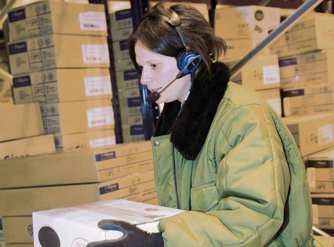 Um operador realiza as tarefas de preparação de pedidos com um sistema de voice picking Um operador realiza as tarefas de preparação de pedidos com um sistema de voice picking